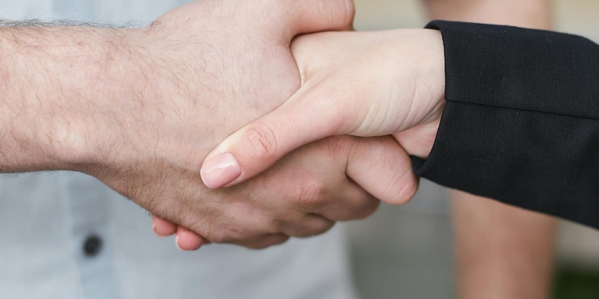 Two professionals shake hands after a successful meeting, symbolizing a landed remote HR role or a strong networking connection.