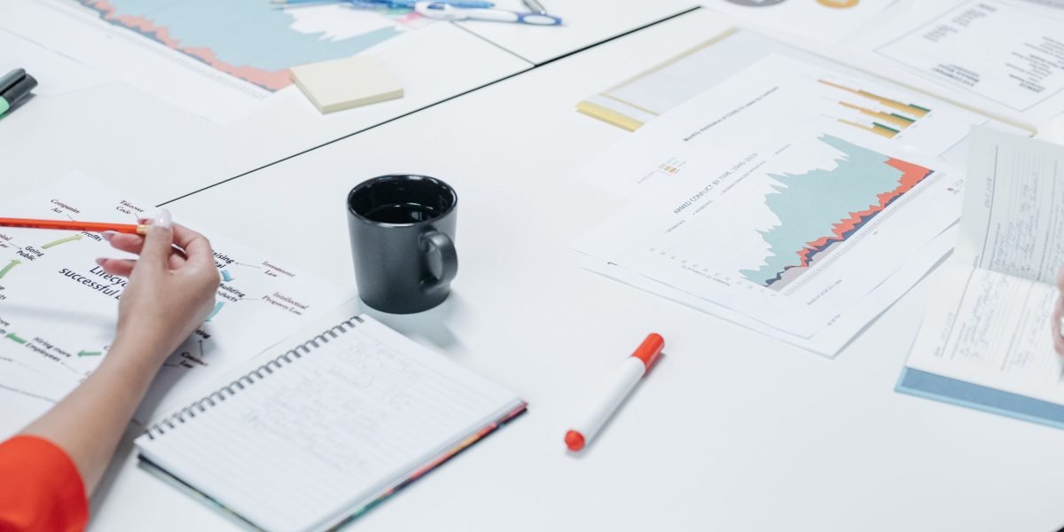 A group of professionals in a modern office setting reviewing documents and charts, indicative of strategic discussions around business risks and investments.