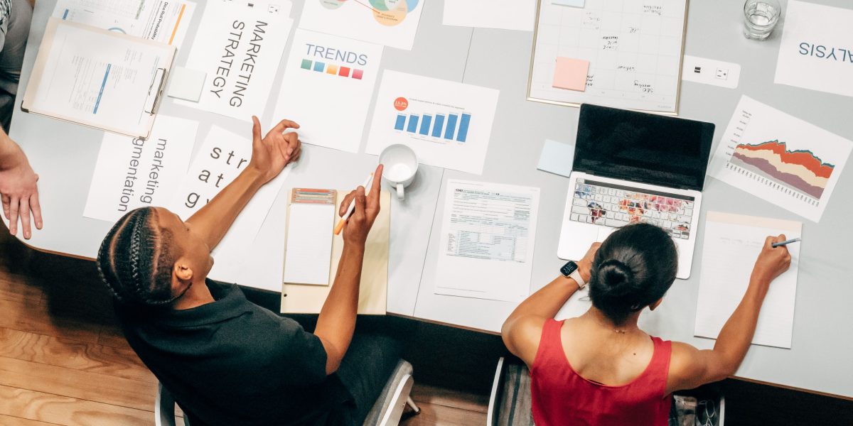 A team of professionals collaborating, possibly brainstorming on a whiteboard, to analyze current AI market trends.