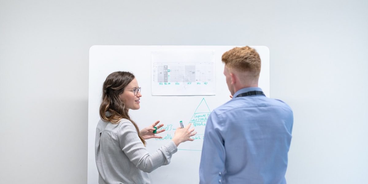 A business professional presenting a clear strategy to a small group, embodying the act of pitching or planning engagement with institutional investors.