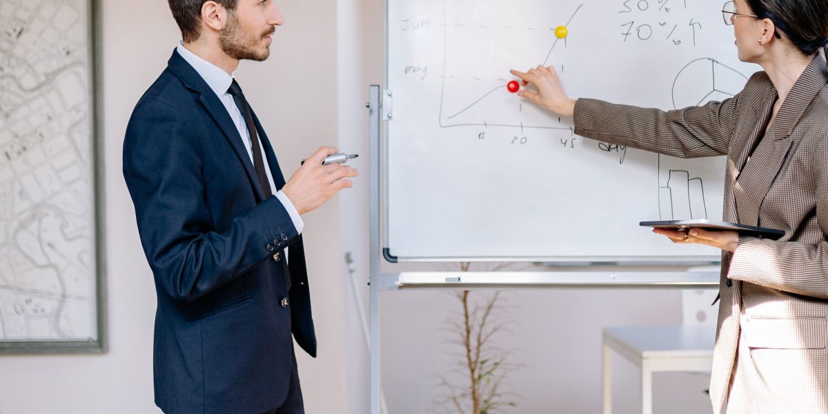 A team actively collaborating and planning future growth strategies on a whiteboard, signifying the need for business reorganization at later stages.