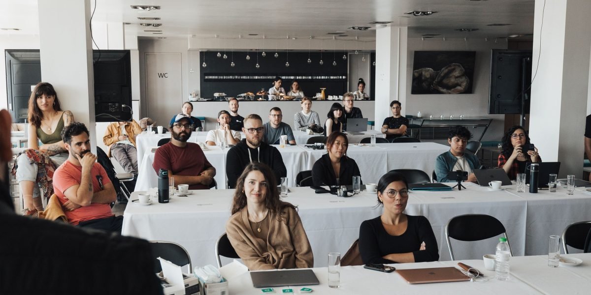 A speaker presenting to a group of attentive professionals in a corporate meeting setting, illustrating effective communication.